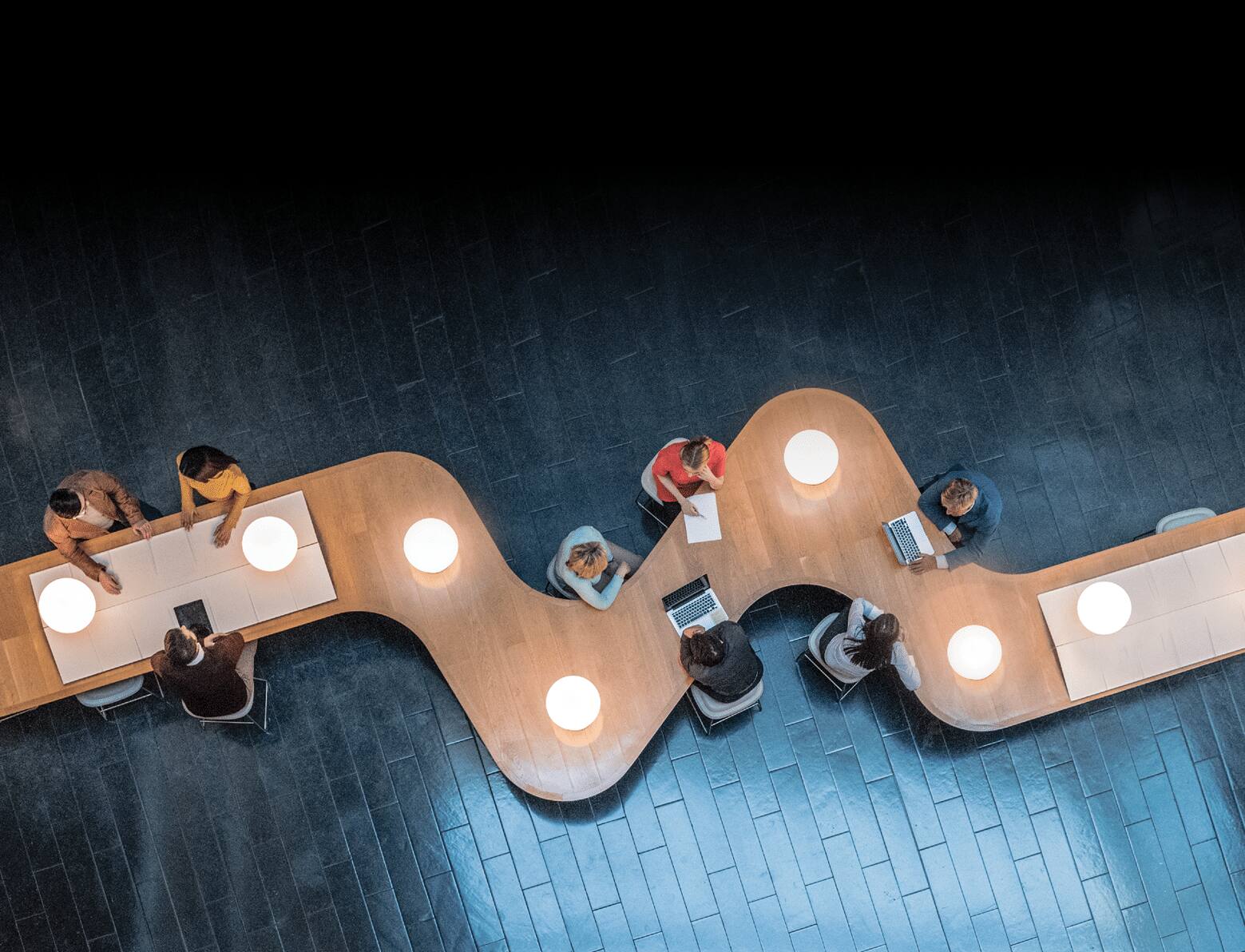 Panoramic overhead view of several business meetings going on in the communal area of a modern office building 